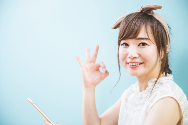 スマホを見てokサインをする笑顔の女性