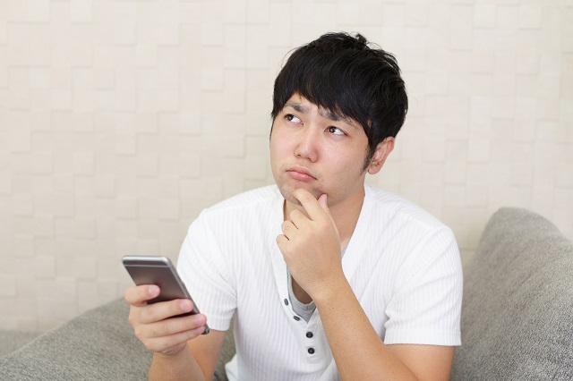 スマホをもって悩んでいる男性
