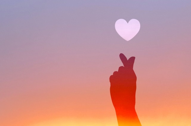 夕焼けに指ハートとハートが浮かぶ様子