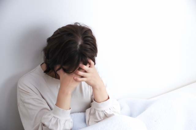 ベッドで頭を抱える女性