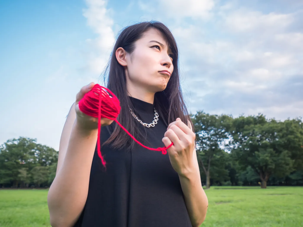 赤い糸を持ち気合いをいれる女性