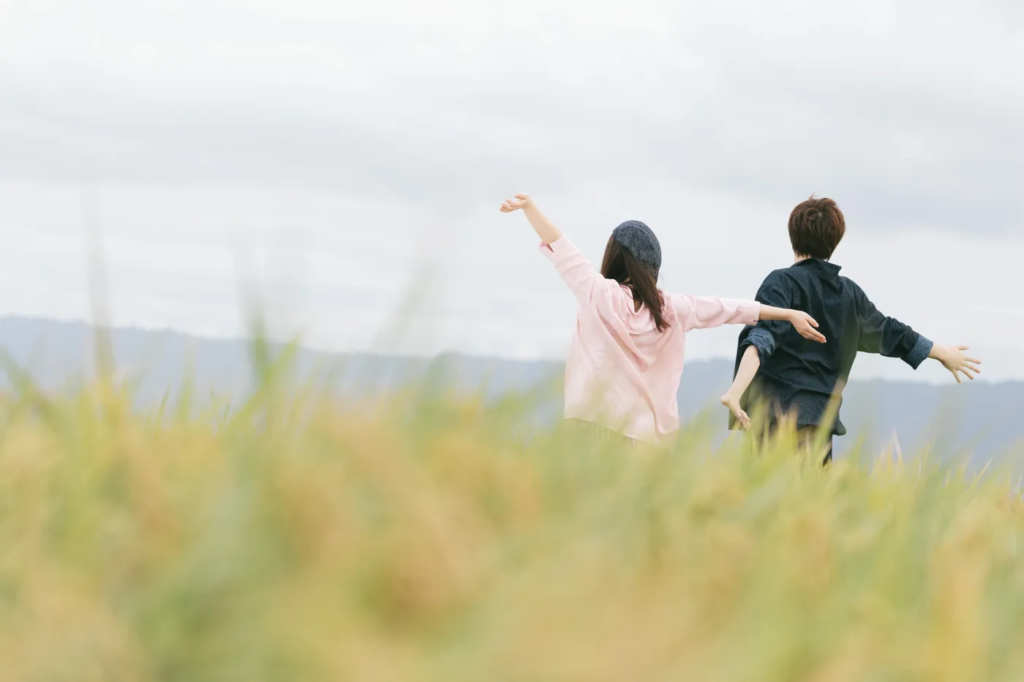 草むらで両手を広げる男女