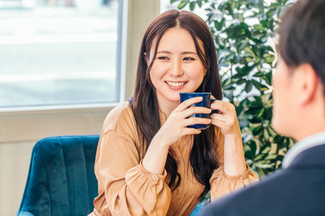 カフェでカップを持ちおしゃべりする女性
